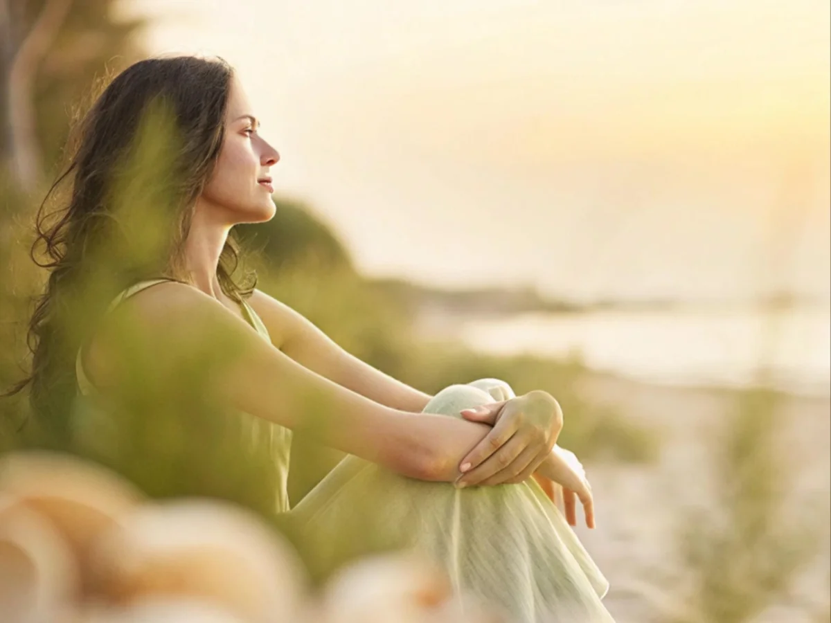 Indian woman sitting peacefully on the beach at sunset, embracing emotional calm and quiet reflection
