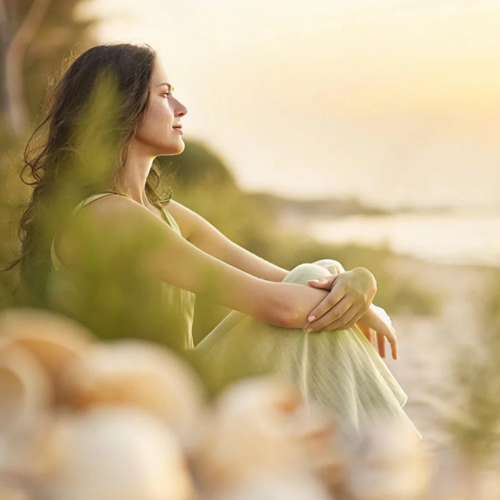 Peaceful woman sitting on beach looking at sunset